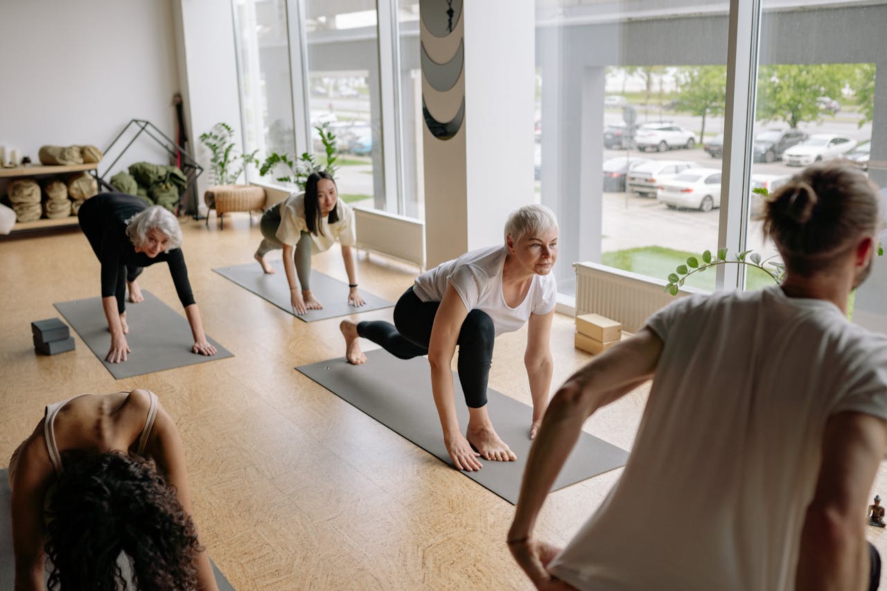Services Adults practicing yoga indoors, focusing on mindfulness and flexibility exercises.